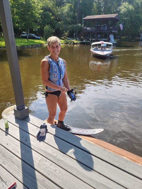 A skier standing on the dock with a ski, ready to go